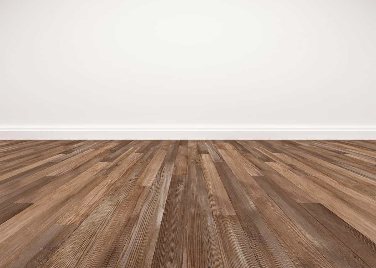 Empty room with white walls and baseboards, and a clean, brown wood plank floor. The image is taken from a low angle, focusing on the flooring, with no furniture or decorations visible.
